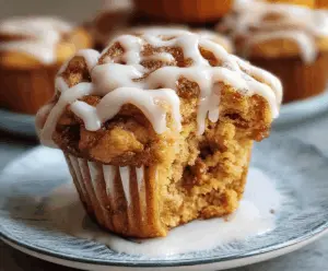 Delicious pumpkin cinnamon roll muffins with swirls of cinnamon and cream cheese frosting on top, perfect for fall desserts and breakfast treats.