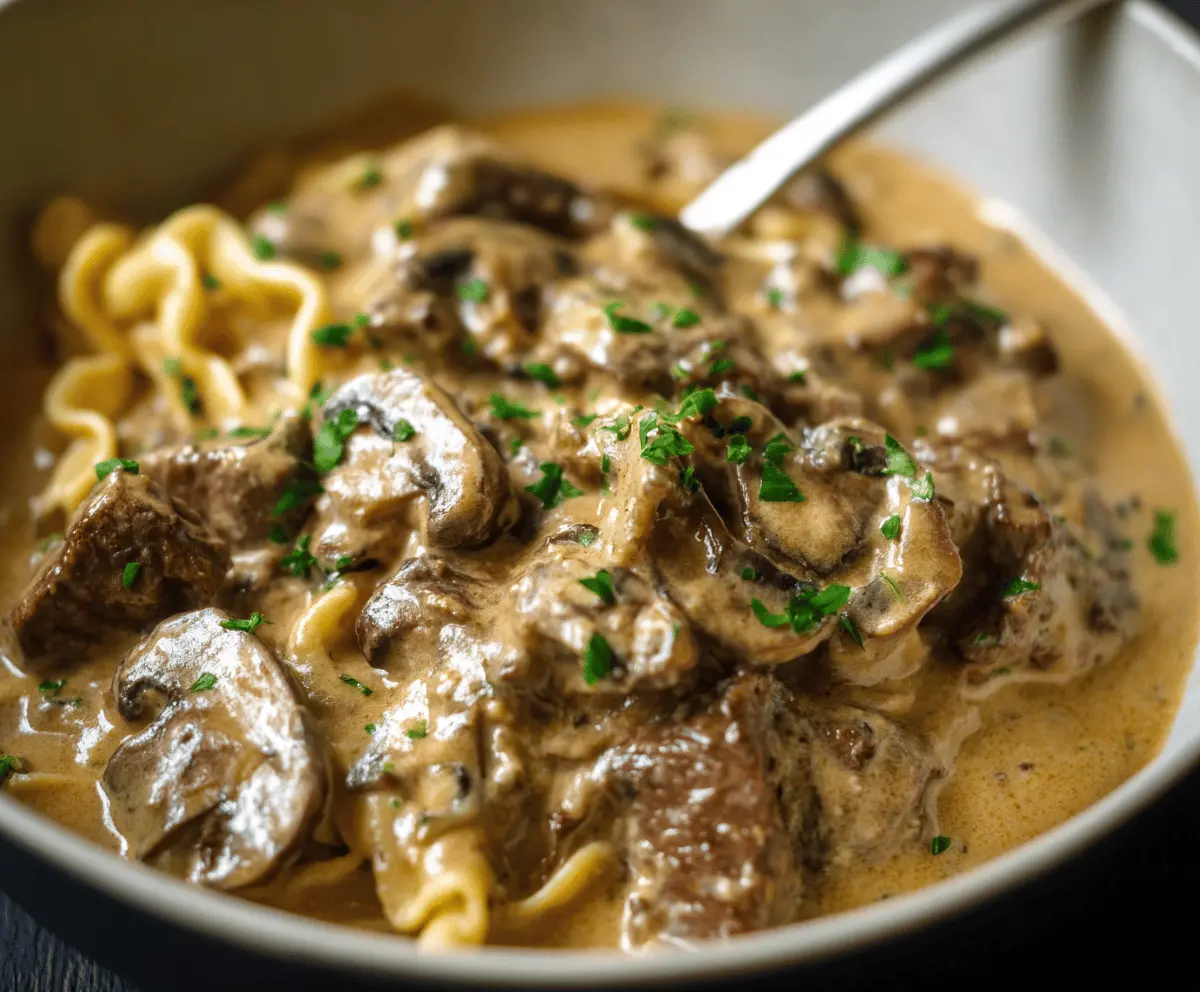 Creamy Gordon Ramsay Beef Stroganoff served with tender beef strips, mushrooms, and a rich sauce garnished with fresh herbs on a plate.