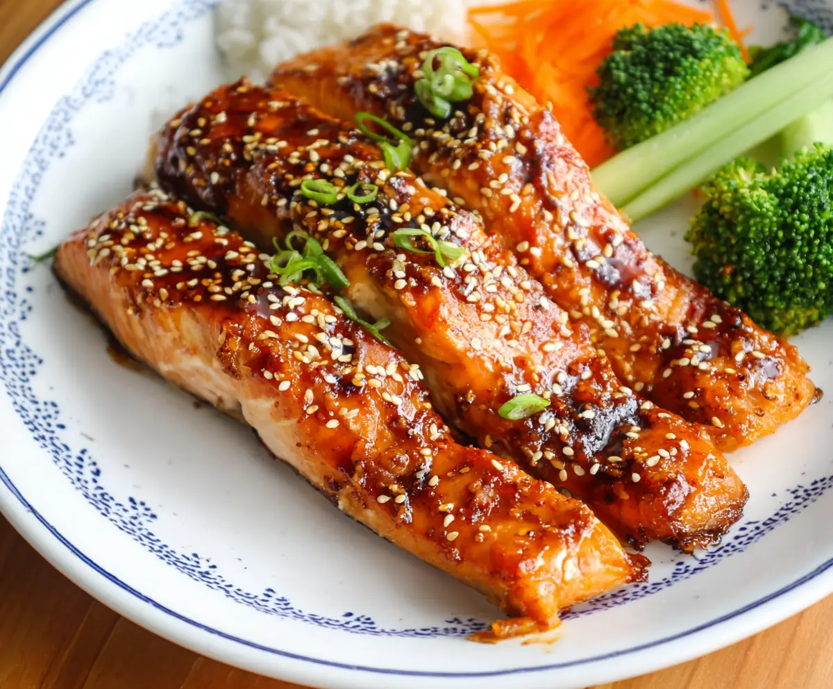 Delicious baked teriyaki salmon served with fresh vegetables on a dinner plate.