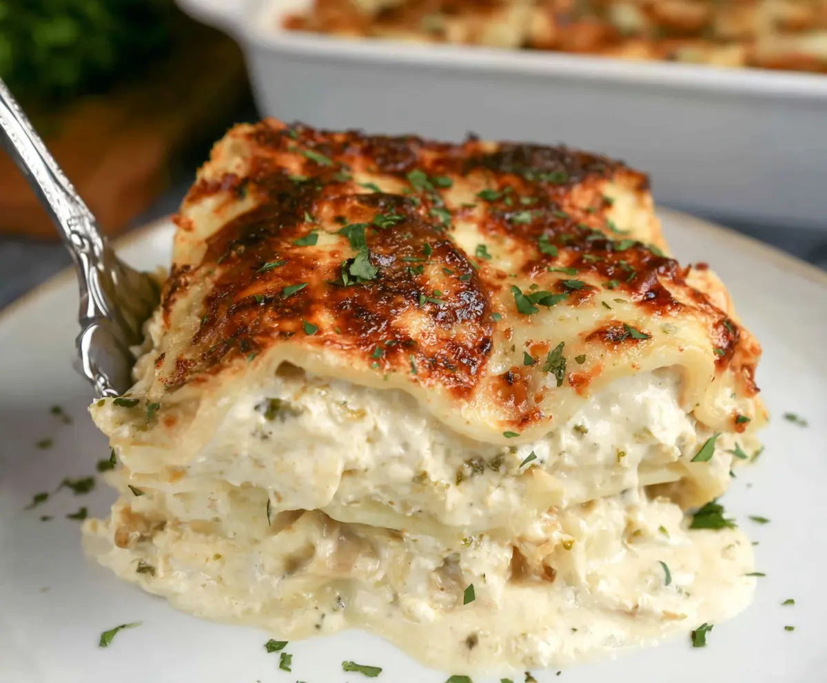 Delicious creamy white lasagna with layers of cheese and tender pasta on a white plate.