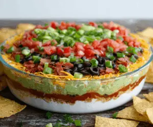 Delicious Ultimate 7 Layer Dip with colorful layers of beans guacamole cheese sour cream and salsa.