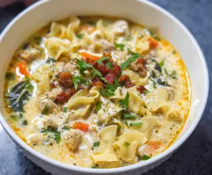 Creamy white lasagna soup with ricotta cheese and spinach in a bowl, garnished with herbs.